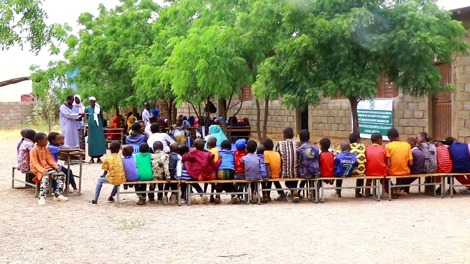 Students gathered outdoors for a community learning activity.